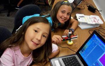 Girls from the Georgia Computes summer camp  next to a laptop